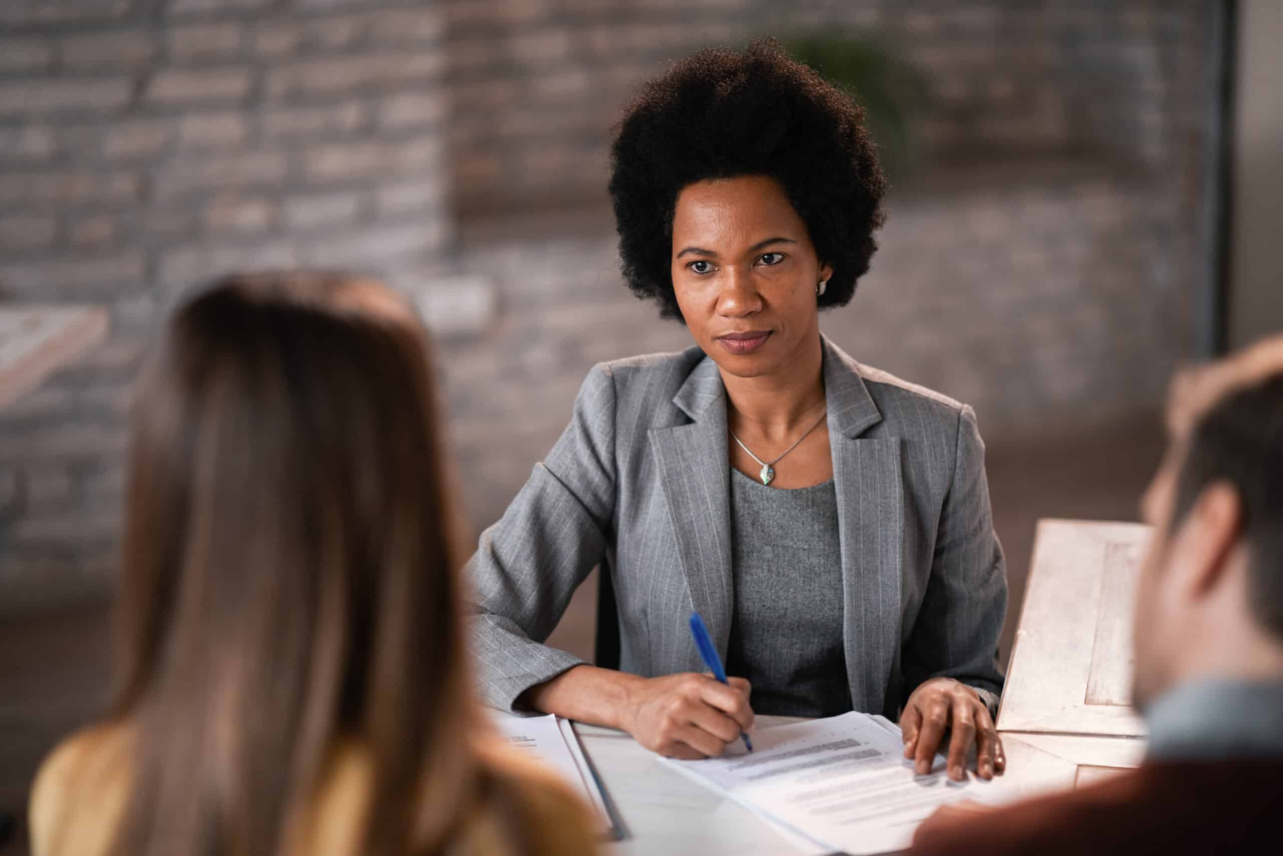 black female financial planner taking notes while having a meeting with her clients.