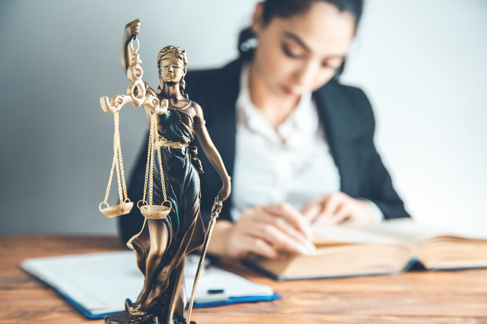 woman hand book with justice lady on desk