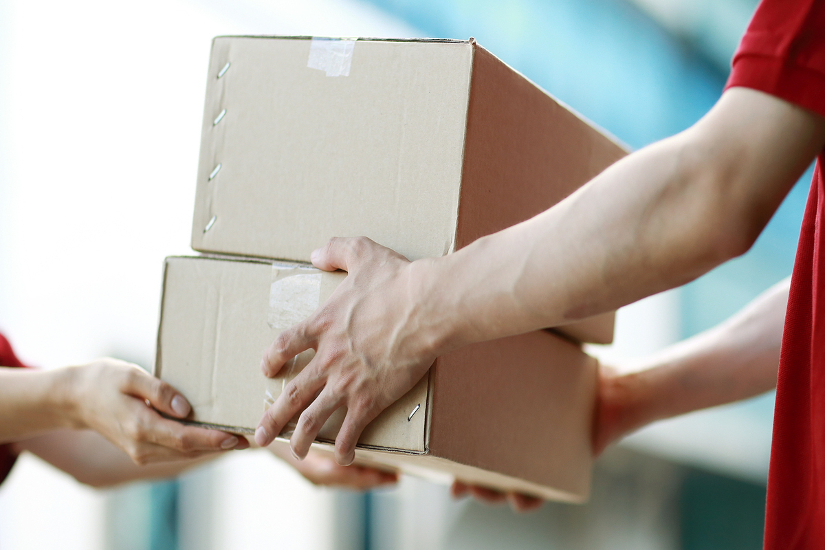 two workers passing boxes in warehouse